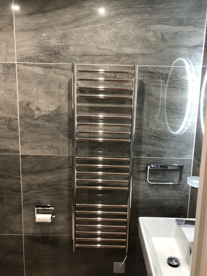 Dark stone-effect wall tiling with heated towel rail