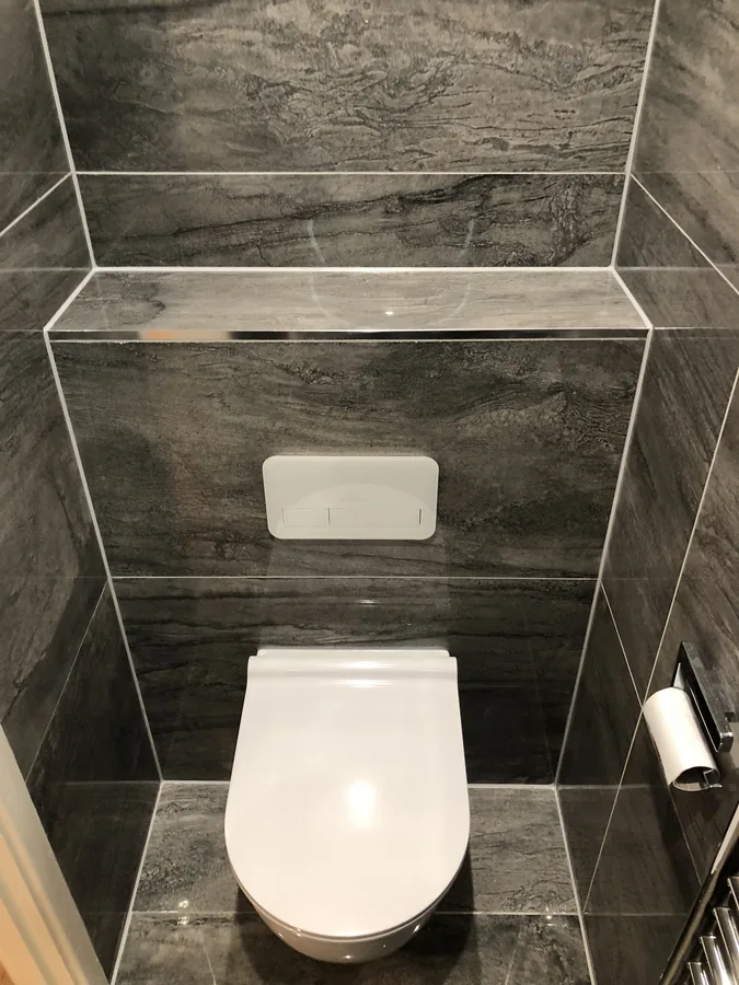 Dark stone-effect tiled wall with recessed niche above the WC