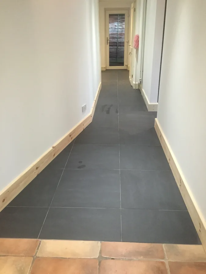Large-format grey floor tiles running the length of a hallway