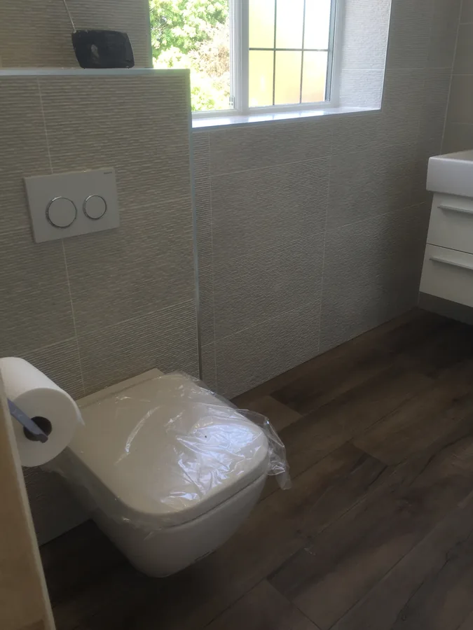 Wall-hung WC and window with textured wall tiling