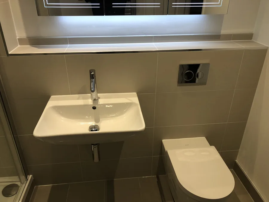 Wall-hung basin below a lit mirrored cabinet