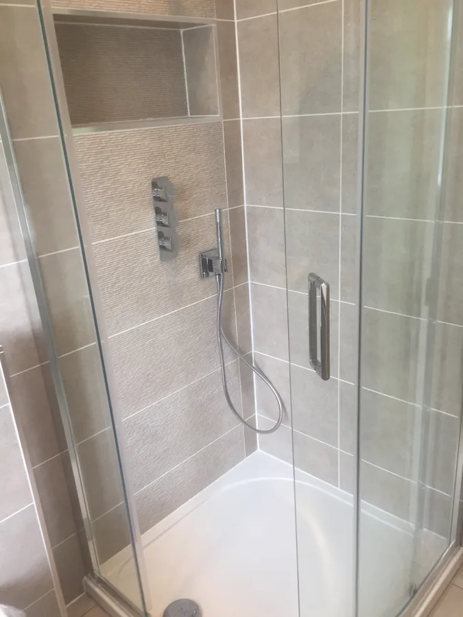 Corner shower enclosure with stone-effect wall tiling